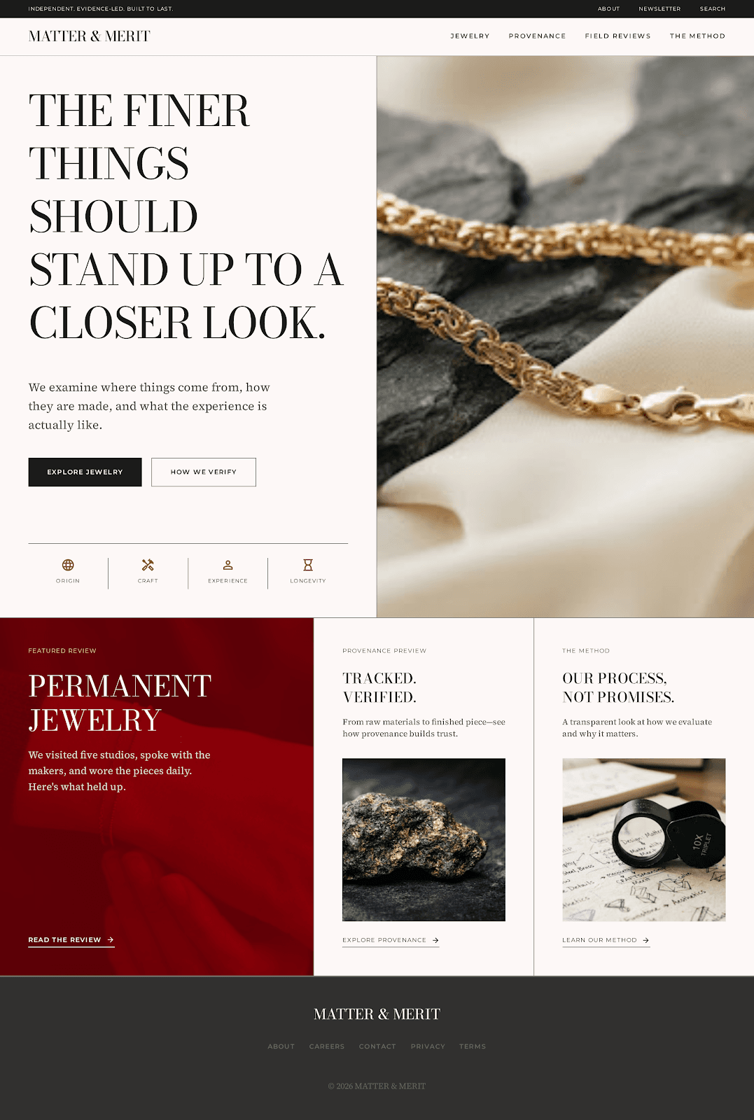 A gold chain resting across slate stone and ivory silk fabric in soft natural light.